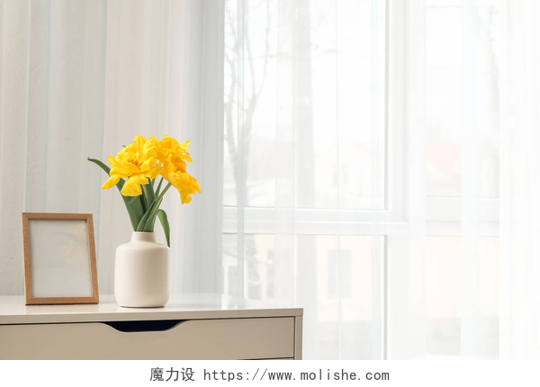 在桌子上的一个白色花瓶在窗边的架子上挂着美丽的花朵和框架